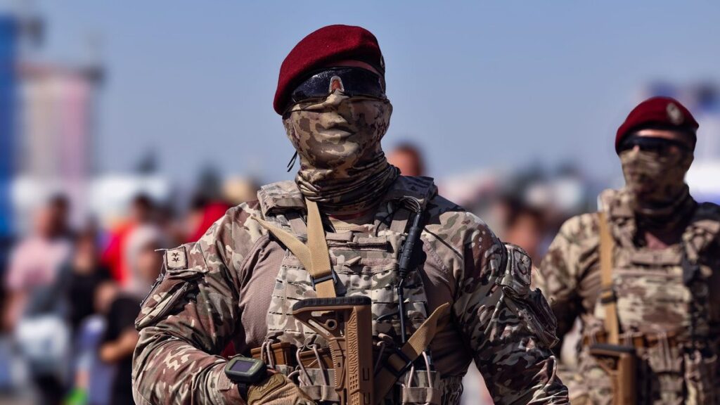 Armed Turkish commandos in camouflage gear marching outdoors during the day.