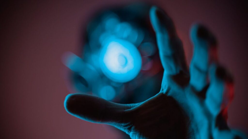 A mysterious hand reaching out towards a blue ethereal light, evoking a sense of wonder.