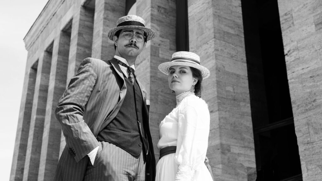 Stylish couple in vintage attire posing at Anıtkabir, Ankara.