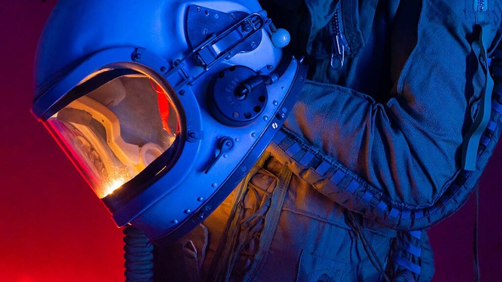 A person in a spacesuit holding an astronaut helmet with colorful lighting.