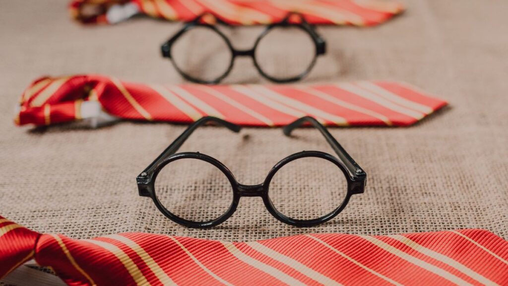 Close-up of round eyeglasses and striped ties on burlap, evoking wizarding world charm.