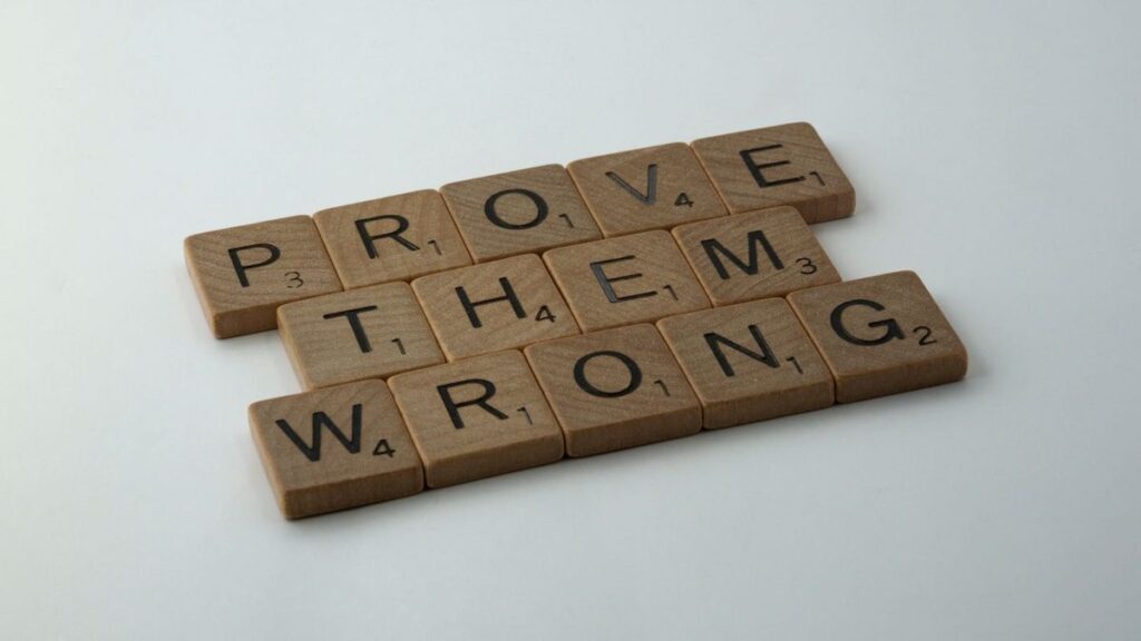 Scrabble tiles spelling the motivational phrase 'Prove Them Wrong' on a neutral background.