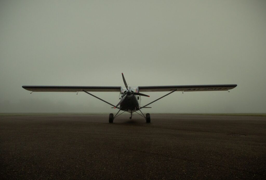 Small propeller plane waiting on a runway in thick fog